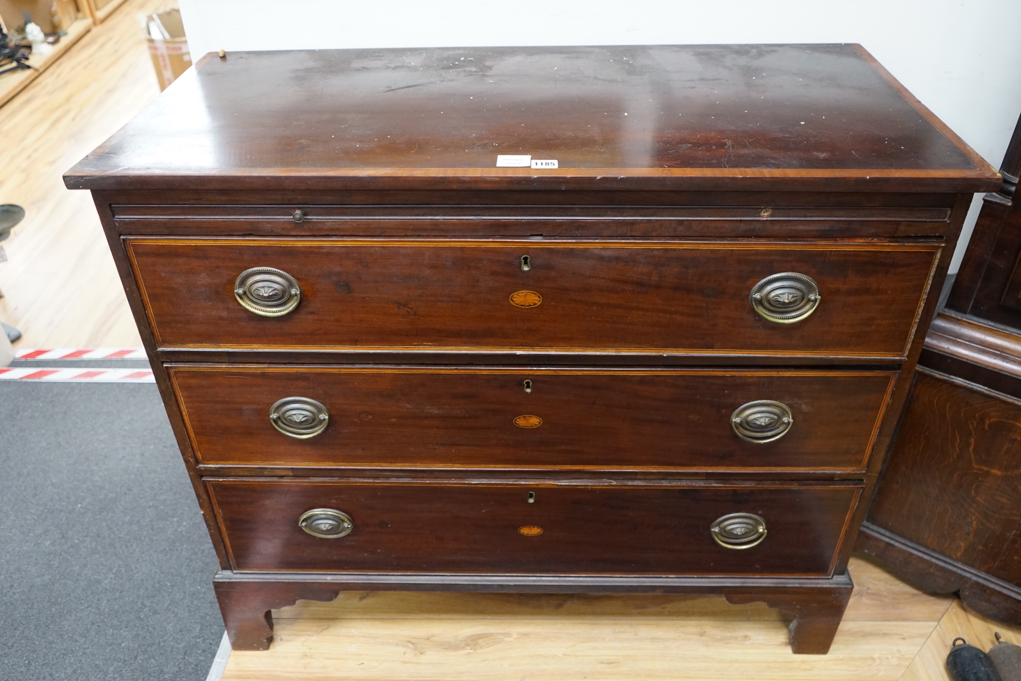 A George III inlaid mahogany three drawer chest with brushing slide, width 109cm, depth 52cm, height 74cm